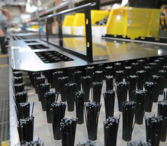 At Metcam, a custom fabricator in Alpharetta, Ga., assemblers slide parts across a series of table brushes for scratch-free production.